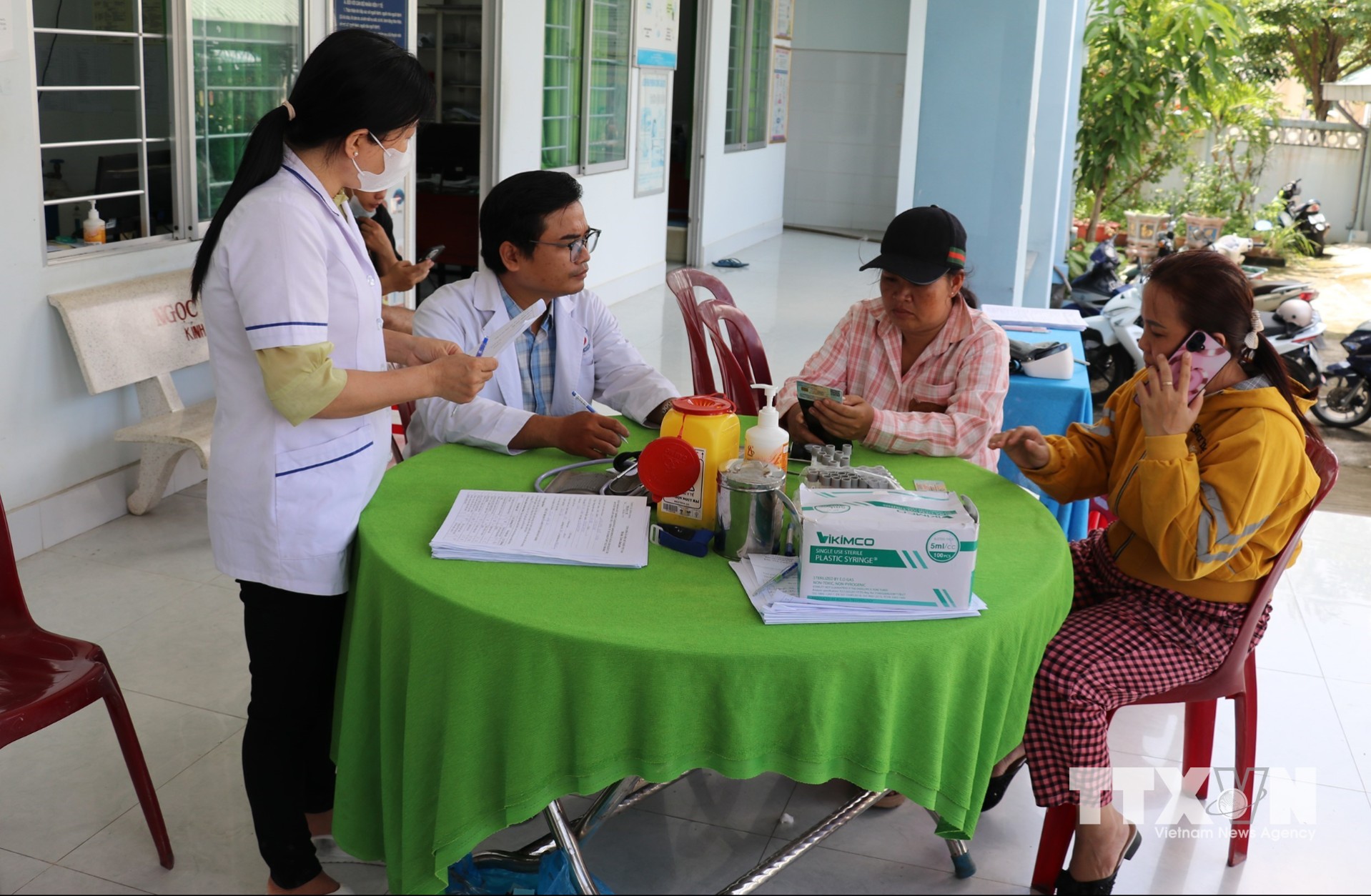 Nhân viên Trạm Y tế xã Bình Ninh, tỉnh Đồng Tháp, hướng dẫn người dân thủ tục tích hợp thẻ bảo hiểm y tế trên VNeID. (Ảnh: Hữu Chí/TTXVN)
